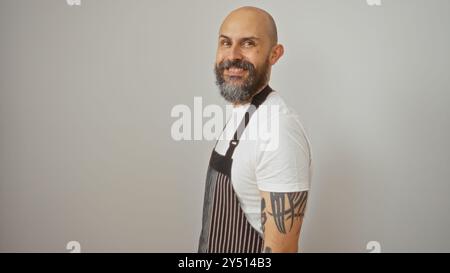 Hispanic man with a beard and tattoos, wearing an apron, smiling against a white background. Stock Photo