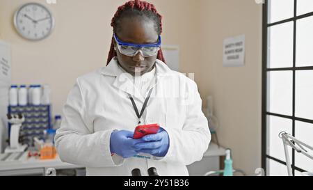 African american woman with braids using smartphone in laboratory Stock Photo