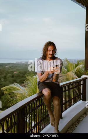 Man using smart phone while sitting on terrace. Stock Photo