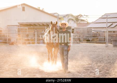 Man walking with horse and kicking up dust Stock Photo