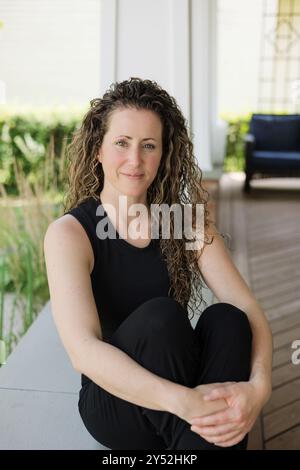 Lifestyle portrait of smiling woman with curly hair outside of home Stock Photo