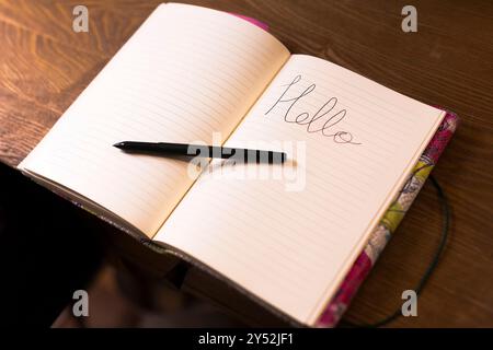 A blank notebook opened on a wooden table with a pen resting beside it Stock Photo