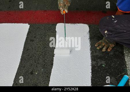 Worker using Paint roller and painting white color on footpath Stock Photo