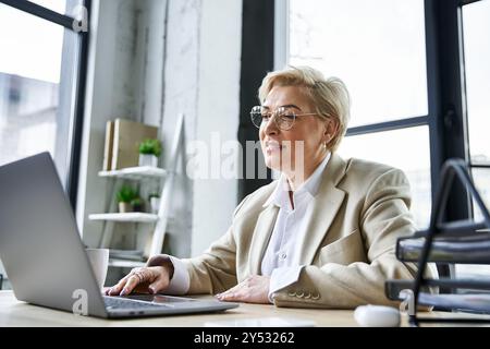 An adult stylish woman engages with her laptop, showcasing elegance in a contemporary workspace. Stock Photo