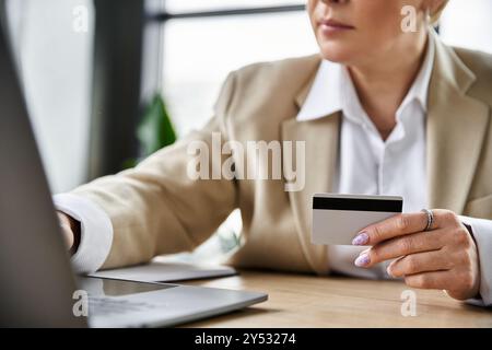 A fashionable adult woman in elegant attire engages in online shopping with a credit card. Stock Photo