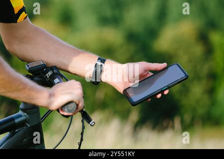 Happy male cyclist sending a text message on his mobile phone. Image of a cyclist on a mountain bike using a smartphone navigator exploring a map and Stock Photo