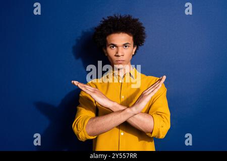 Portrait of nice young man crossed arms wear yellow shirt isolated on dark blue color background Stock Photo