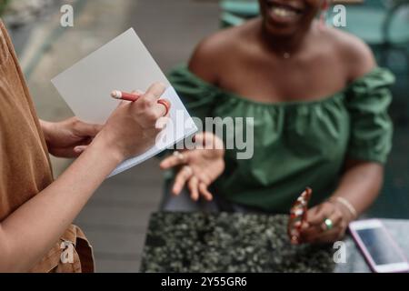 High angle shot of unrecognizable female hands holding pen while taking order Stock Photo