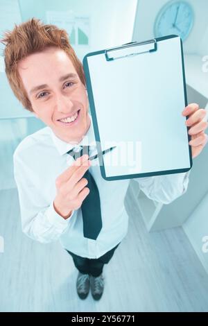 Businessman is smiling and holding a blank clipboard and pen, inviting viewers to imagine their own message or advertisement Stock Photo
