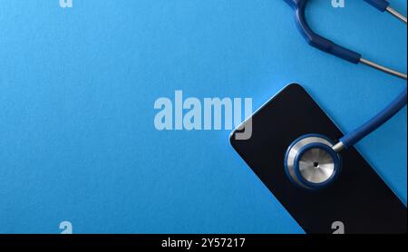 Detail of health background and online healthcare help with stethoscope on smartphone on blue isolated background. Top view Stock Photo