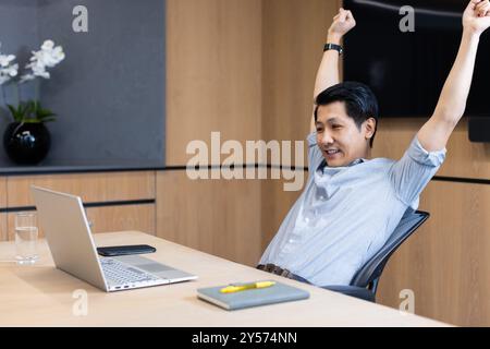 Stretching at desk, asian man taking break from working on laptop in office Stock Photo