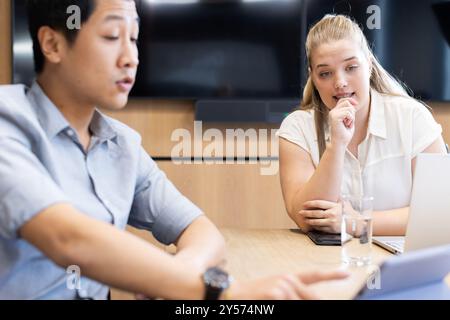 Discussing business strategy, multiracial colleagues using laptop and tablet in office meeting Stock Photo