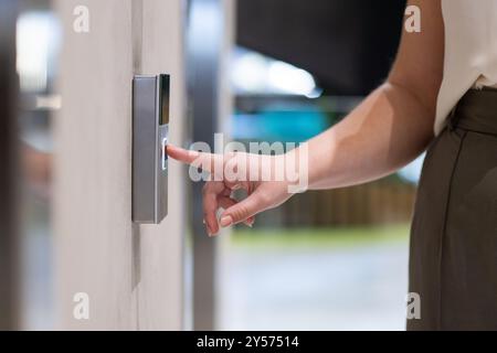 Pressing fingerprint scanner, woman accessing secure entrance of office building Stock Photo