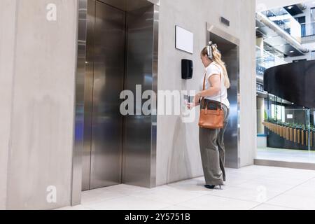Pressing elevator button, businesswoman in modern office building lobby Stock Photo