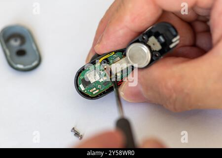 London. UK- 09.18.2024. A technician repairing a wireless head phone using a screwdriver. Stock Photo