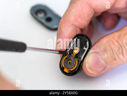 Close up of a technician repairing a wireless head phone using a screwdriver. Stock Photo