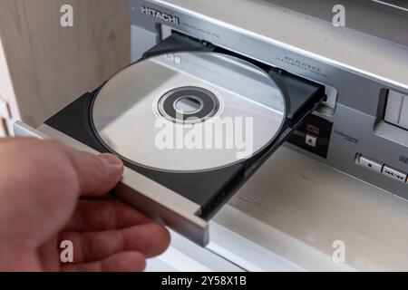 London. UK- 09.18.2024. A person inserting a digital video disc into a Hitachi DVD player. Stock Photo