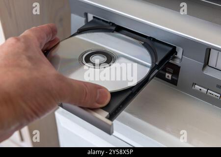 A person inserting a digital video disc into a DVD player. Stock Photo