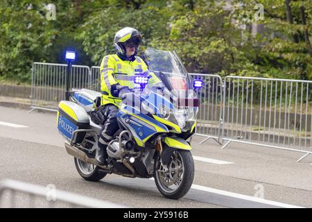 A police officer rides a motorbike with blue lights during an operation, surrounded by barriers on a road, Stuttgart, Baden-Wuerttemberg, Germany, Eur Stock Photo