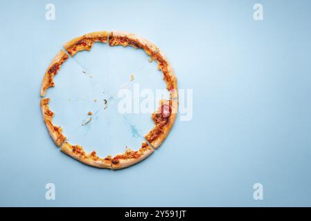 Pizza pepperoni leftovers top view on a blue background. Homemade pizza remainings and traces of grease on cardboard Stock Photo