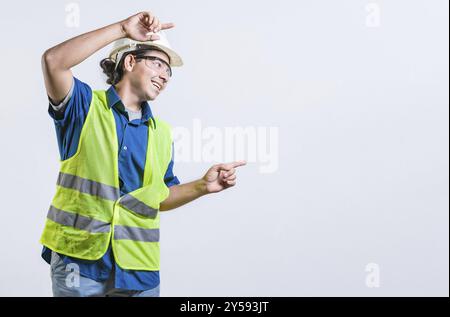 Smiling latin engineer pointing to the side with both fingers isolated. Happy male builder pointing an advertisement isolated Stock Photo