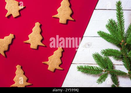 Minimalist Christmas image with ginger cookies in shape of an Xmas tree on a red background and a green fir twig on a white background Stock Photo