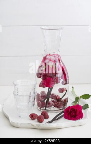 Infused water with raspberries, rose petals and vanilla beans in a pitcher Stock Photo