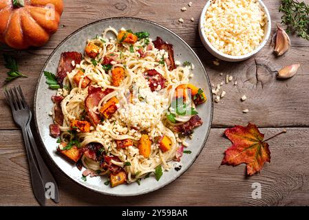 Pumpkin and Bacon Pasta with grated parmesan cheese. Homemade spaghetti pumpkin pasta served on wooden background. Seasonal autumn food. Pumpkin Carbo Stock Photo