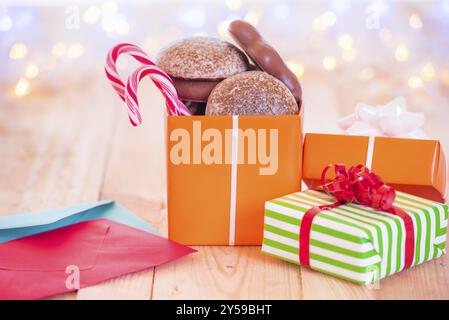 Jolly image with wrapped gifts, colorful envelopes, on a wooden table with Christmas bokeh lights in the background Stock Photo