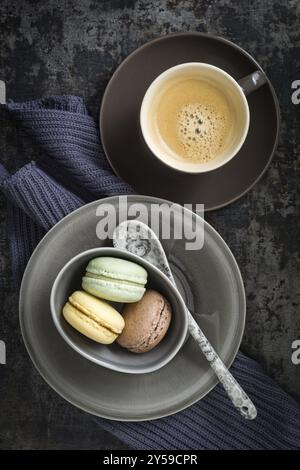 Colourful macarons in a small cup with y cup of coffee Stock Photo