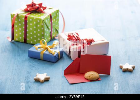 Red envelope opened and a small card for a message on a blue wooden table surrounded by gift boxes Stock Photo