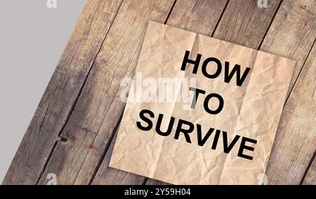 How To Survive text written on paper torn top view on background. Business concept. Stock Photo