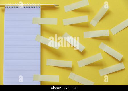 Multitude of blank yellow stickers fixed on a spiral notebook and the office desk Stock Photo