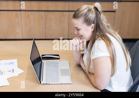 Working on laptop, woman analyzing business charts and data at office desk Stock Photo