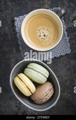 Colourful macarons in a small cup with y cup of coffee Stock Photo