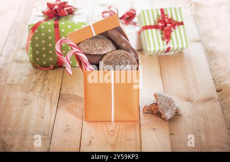 Top open gift box full of gingerbread and colorful candies on a wooden table Stock Photo