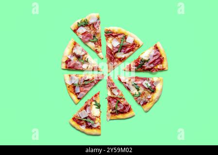 Delicious homemade prosciutto pizza isolated on a green background. Sliced pizza minimalist on a colorful table Stock Photo