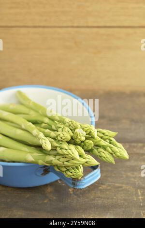 Fresh green asparagus in a colander on a wooden table Stock Photo
