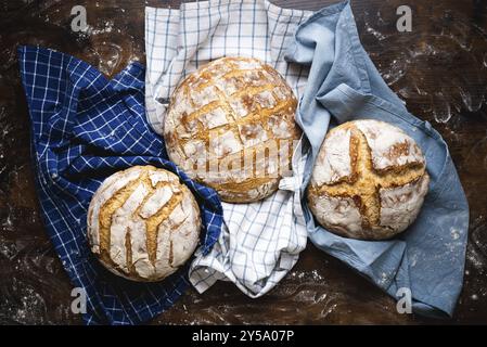 Above view with three homemade sourdough loaves of bread on towels. Freshly baked and delicious white bread Stock Photo
