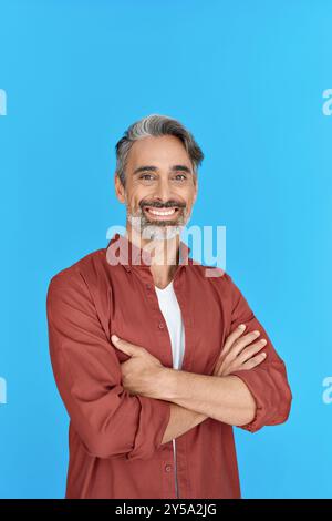 Happy middle aged man standing isolated on blue background. Vertical portrait. Stock Photo