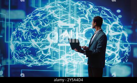IT expert solving tasks on laptop device, running artificial intelligence programming scripts. Indian man using notebook to write lines of code for AI applications development, camera B Stock Photo