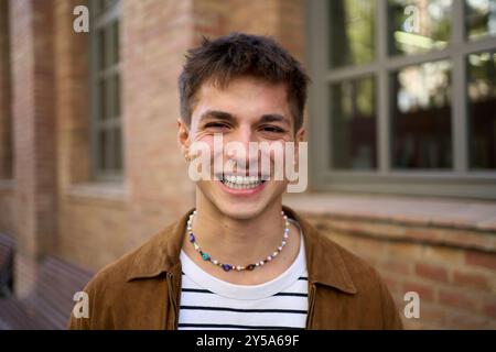 Portrait of happy young handsome Caucasian man with big smile posing looking at camera outdoors. Stock Photo