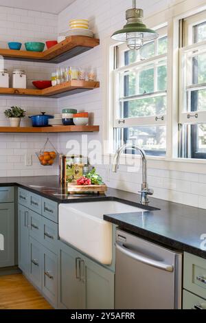 Sunny bright kitchen farmhouse sink with open shelves in background Stock Photo