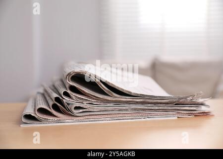 Stack of newspapers in different languages on table indoors Stock Photo