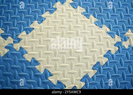 Close-up photo of interlocking blue and white puzzle mats. The mattress background is made of soft and soft foam Stock Photo