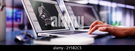 African American Female Engineer Developing Mechanical Parts Using 3D CAD Software on Laptop at Factory Office Stock Photo