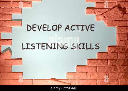 Business and Develop active listening skills concept. DEVELOP ACTIVE LISTENING SKILLS on the wall under the dismantled bricks Stock Photo