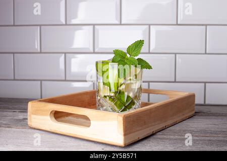 Original caipirinha cocktail on a wooden tray. White tiles in the background. Recipe with lime, mint, sugar, rum and ice. Stock Photo