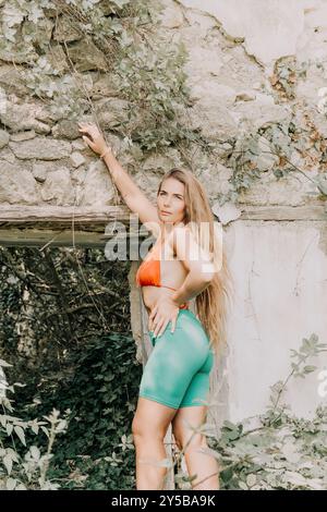 Woman, Bikini, Wall - A woman in a bikini poses against a stone wall with greenery. Stock Photo