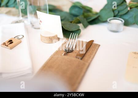 Wedding decor. Beautiful event venue. Indoor round reception table with flowers and chairs. Compositions of flowers and plants in  wooden stands. Stock Photo